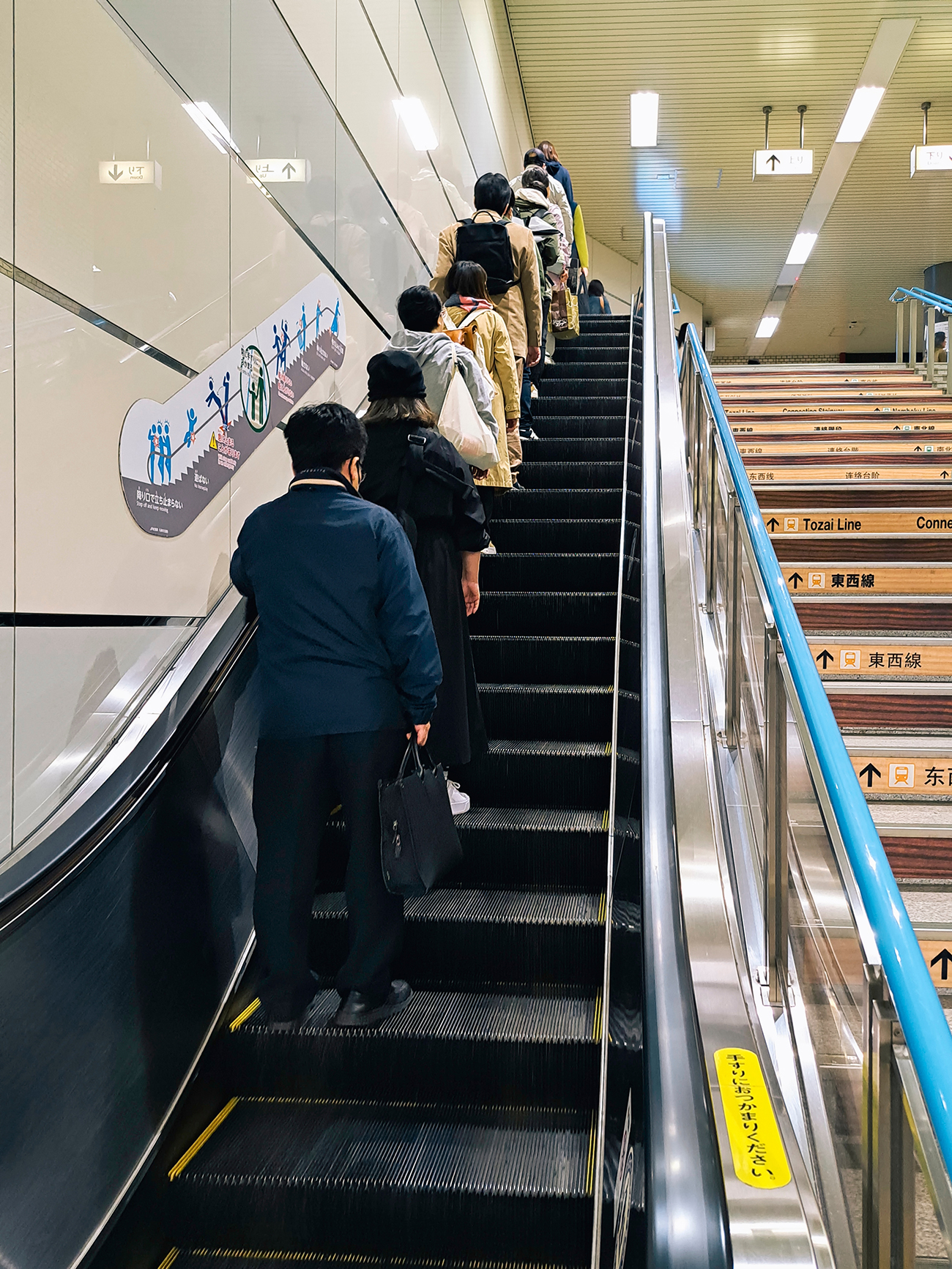 Passengers standing on the left side of an escalator in Tokyo, leaving the right side open