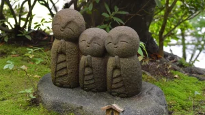 Three small stone Jizo statues surrounded by moss and greenery in Japan